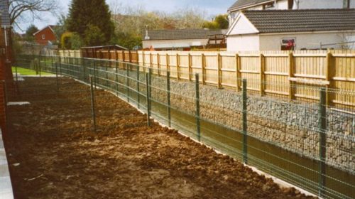 A gabion retaining wall is used on either side of this river